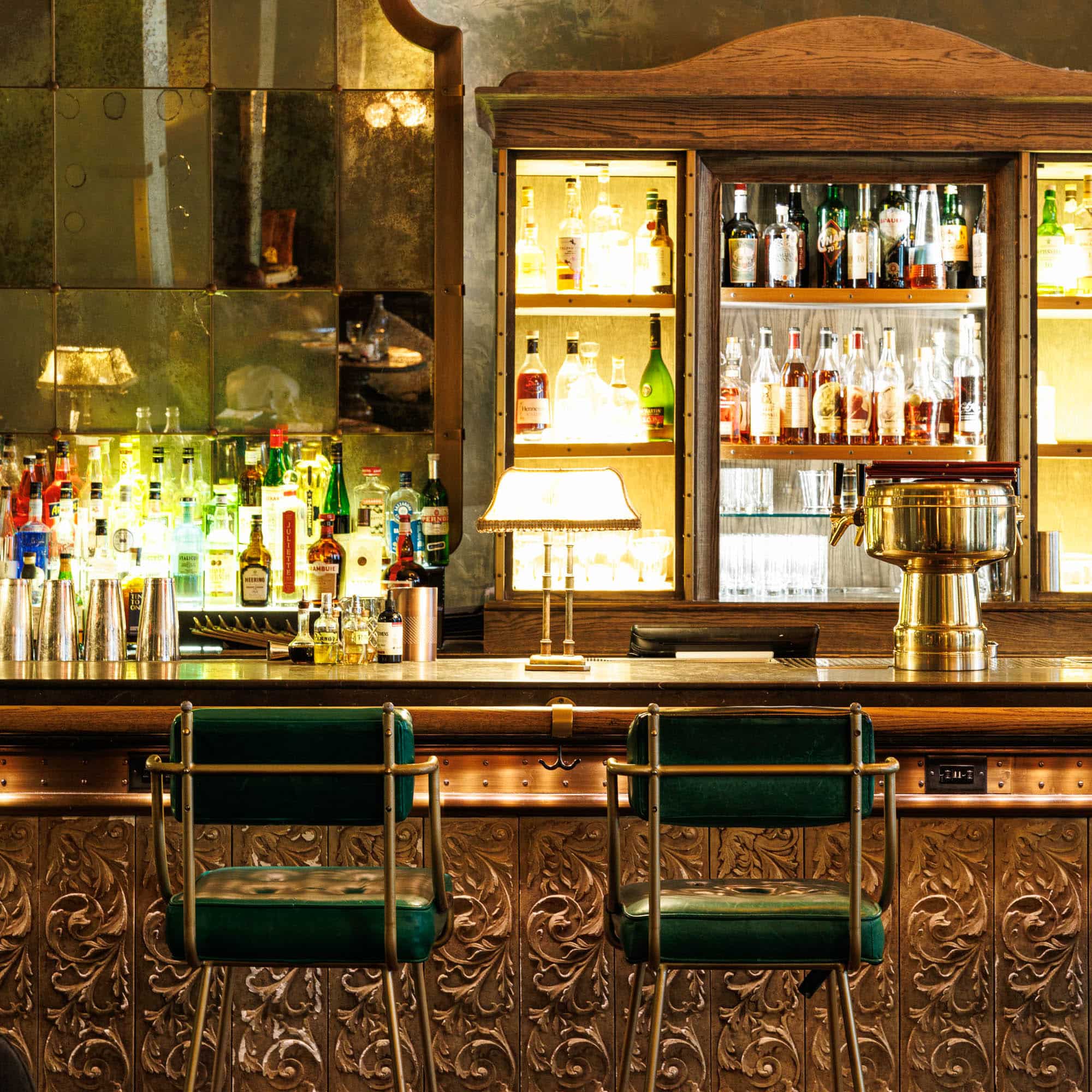 two green bar stools with a fully stocked bar in the background